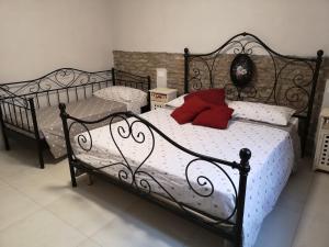 czarne łóżko z 2 czerwonymi poduszkami w obiekcie Appartamento Le Cicale w mieście Ferrara