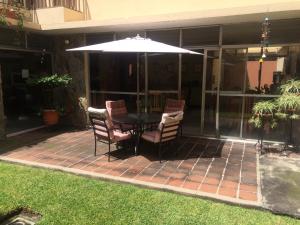 eine Terrasse mit einem Tisch und Stühlen unter einem Sonnenschirm in der Unterkunft Hostal Los Lagos Inn in Guatemala