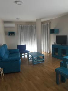 a living room with a blue couch and a table at Apartamento Turístico “El Yugo” in Arguedas