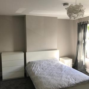 a bedroom with a bed and a dresser and a window at Two Little Ducks Guesthouse in Ellesmere Port +4 photos