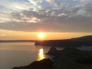 a sunset over a body of water with the sun setting at Ortari@70 in Bishopston