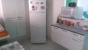 a kitchen with a white refrigerator and a microwave at Condominio casas do campo in Campo Grande