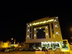 a building with cars parked in a parking lot at night at Ramis Serviced Apartments in Buraydah
