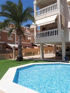 a villa with a palm tree and a swimming pool at Apartamento Costa Azahar in Santa Pola