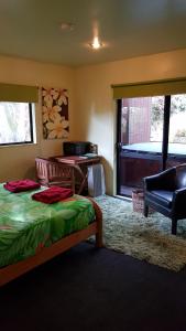 a bedroom with a bed and a chair and a window at Pohutukawa Coast BnB in Te Puru