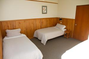 two beds in a room with wooden walls at Stronechrubie Accommodation and Restaurant in Mount Somers