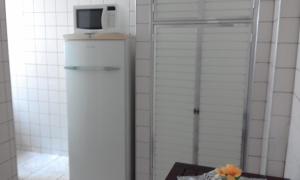 Elle comprend un réfrigérateur blanc et un four micro-ondes. dans l'établissement apto 1 quarto, Boqueirão Praia Grande, à Praia Grande