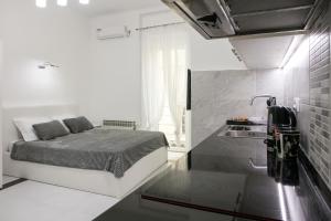 ein kleines weißes Schlafzimmer mit einem Bett und einem Waschbecken in der Unterkunft Natalie's Studio in Belgrad