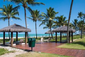 a wooden deck with chairs and umbrellas on the beach at Apto Oka Beach Residence in Porto De Galinhas