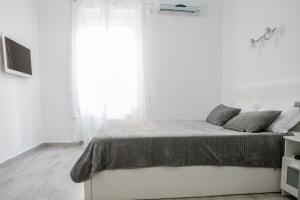 een witte slaapkamer met een bed en een groot raam bij Natalie's Suite in Belgrado