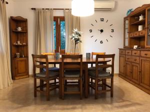 a dining room table with chairs and a clock on the wall at Casa Coromines in Alcudia