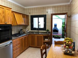 a kitchen with wooden cabinets and a table with a bowl of fruit at Casa Coromines in Alcudia