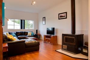 a living room with a couch and a wood stove at Sapphire Cottage in Glen Innes