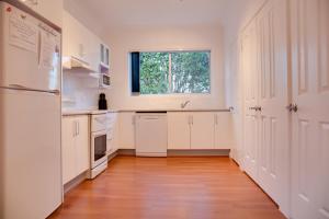 a kitchen with white cabinets and a window at Sapphire Cottage in Glen Innes