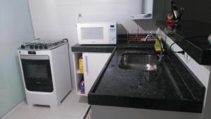 eine kleine Küche mit einer Spüle und einer Mikrowelle in der Unterkunft Le Bon Vivant in Arraial do Cabo
