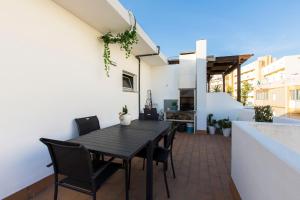 a patio with a black table and chairs on a balcony at Maria Rita Faro Rooftop Apartment in Faro