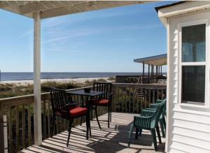 a porch with a table and chairs and the beach at Blue Crab Cove in Oak Island