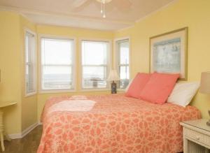 a bedroom with a bed with red pillows and windows at Blue Crab Cove in Oak Island
