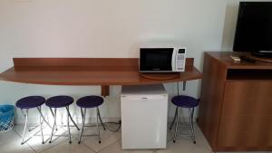 eine Theke mit Hockern unter einem Tisch mit einer Mikrowelle in der Unterkunft 1307 AP 2 Quartos Shopping , banheira de hidro privativa , bebidas liberadas nas piscinas , e com internet no ap, proximo ao shopping singapura in Caldas Novas