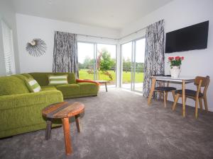 a living room with a green couch and a table at The Rise in Waimate North