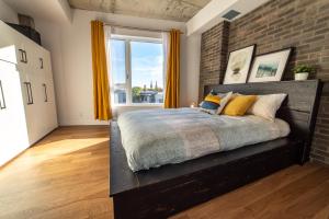 ein Schlafzimmer mit einem großen Bett mit Ziegelwand in der Unterkunft Aux Havres Urbains - Le Penthouse de la 3ième Avenue in Québec