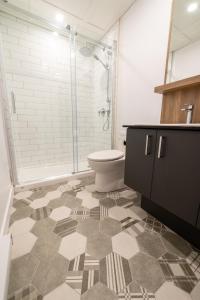 e bagno con servizi igienici e doccia in vetro. di Aux Havres Urbains - Le Penthouse de la 3ième Avenue a Québec