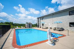 una piscina con sillas y sombrillas junto a un edificio en Motel 6-London, KY, en London