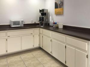 a kitchen with white cabinets and a black counter top at Motel 6-Bremen, GA in Bremen