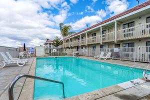 - une piscine avec des chaises en face de l'hôtel dans l'établissement Studio 6-Buttonwillow, CA, à Buttonwillow