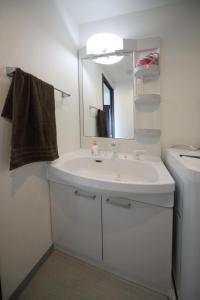 uma casa de banho com um lavatório branco e um espelho. em EX Itoman Apartment 703 em Itoman