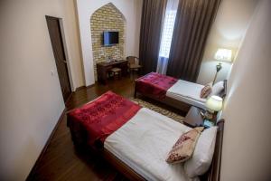 a bedroom with two beds and a dresser at Arkanchi Hotel in Khiva