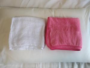 two towels sitting on top of a bed at Cat Cafe & Stay Cultus's Home in Otaru
