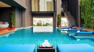 a swimming pool with a pair of white shoes in it at Mövenpick Residences Ekkamai Bangkok in Bangkok