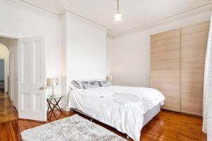 - une chambre blanche avec un lit et du parquet dans l'établissement The Crofts, à Melbourne