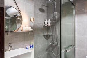 a bathroom with a shower with a sink and a mirror at Wuhan Wuchang·Star City· Locals Apartment 00121940 in Wuhan +18 photos