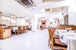 un ristorante con sala da pranzo con tavoli e sedie di Hotel Gandharva Shivajinagar a Pune