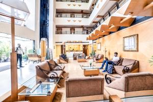 a lobby with two people sitting in chairs in a building at Hotel Gandharva Shivajinagar in Pune