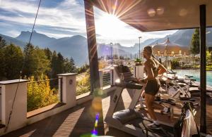 a man sitting on a bench in front of a boat at Hotel Albion Mountain Spa Resort Dolomites in Ortisei