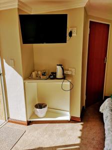 a room with a tv on a wall with a shelf at Rest-a-While Guest House - Pretoria in Pretoria