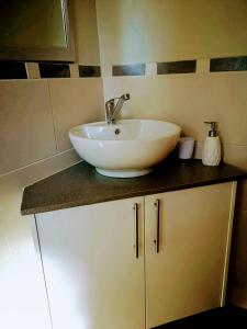 a bathroom with a white sink on a counter at Rest-a-While Guest House - Pretoria in Pretoria