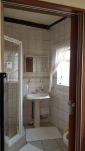 a bathroom with a sink and a shower at Rest-a-While Guest House - Pretoria in Pretoria