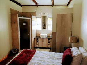 a bedroom with a bed and a bathroom with a sink at Rest-a-While Guest House - Pretoria in Pretoria