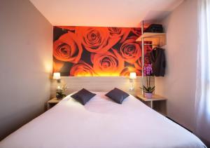 Un dormitorio con una cama blanca y una pintura de rosas. en Hôtel Inn Design Resto Novo Vannes en Theix