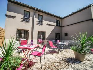 a patio with pink chairs and tables in front of a building at Hôtel Inn Design & Restaurant Vannes Theix-Noyalo in Theix