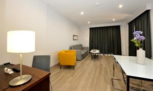 un soggiorno con sedia gialla e divano di Hotel Salobreña Suites a Salobreña
