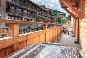 terraza de madera con mesa y sillas en el balcón en PERCE NEIGE 1ER, en Morzine