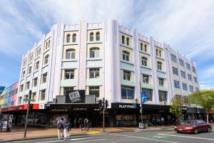 een groot wit gebouw in een stadsstraat met een auto bij Aura Hotel in Wellington