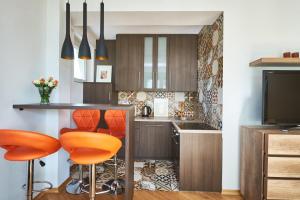 a kitchen with orange bar stools and a tv at Noctis Apartment Tamka in Warsaw