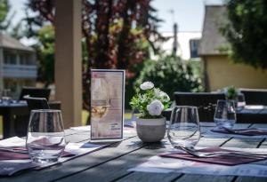 una mesa de madera con copas de vino y un cartel en ella en Hôtel Inn Design Resto Novo Sablé en Sablé-sur-Sarthe