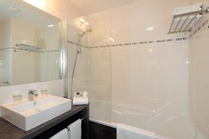 een witte badkamer met een wastafel en een douche bij Appart'City Confort Grenoble Inovallée in Montbonnot-Saint-Martin